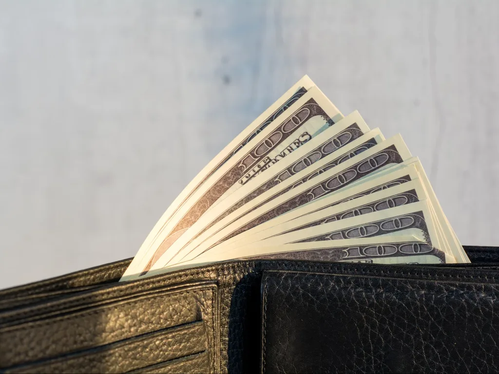 Plånbok med sedlar bredvid en kalkylator – nöjesbudget för spel om pengar.